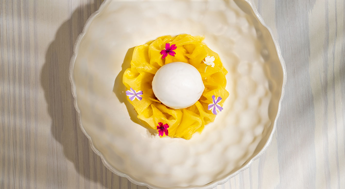 White egg nestled in yellow tissue paper with colorful small flowers on cream-colored surface
